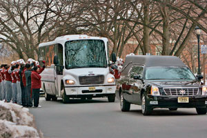 The football team salutes the funeral cortege of Fred M. Kirby II as it passes through campus.