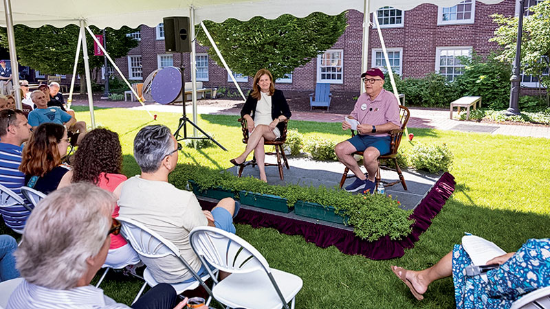 Nicole Farmer Hurd and Tony Fernandez speak to a group of alumni seated in chairs under an outdoor tent