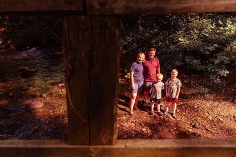 Lauren and Chris Anderson stand in a creek with their children