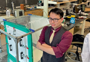 Joe Woo stands with arms crossed in a lab space